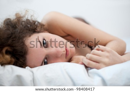 Portrait of a sensual young woman lying on bed. Shallow depth of field.