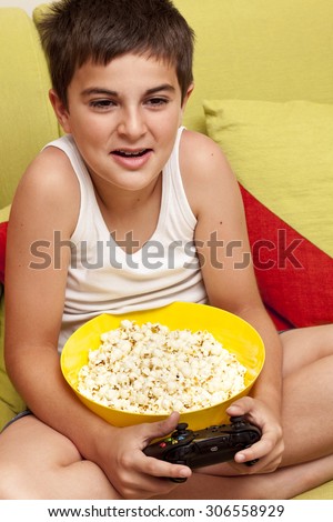 Little boy playing video games and eating popcorn