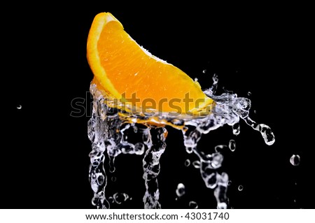 Orange is dropped into water splash on black.