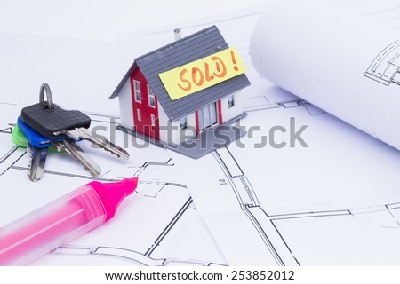 The image shows a house, keys and a architect's plan