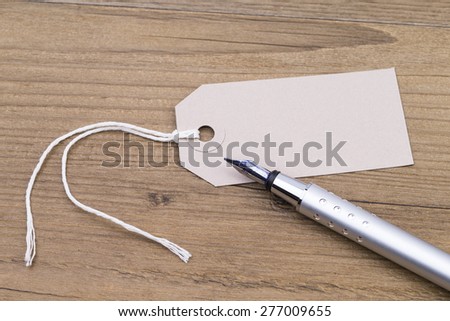Image shows a blank label and a pen on a wooden table