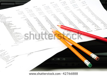 Business profit & loss statements on laptop with pencils