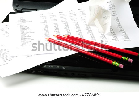 Business profit & loss statement on laptop with red pencils