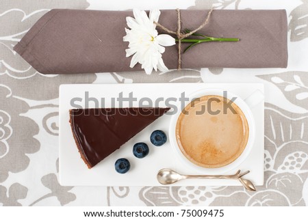 Chocolate tart with bilberry and a cup of coffee on a cute table appointments