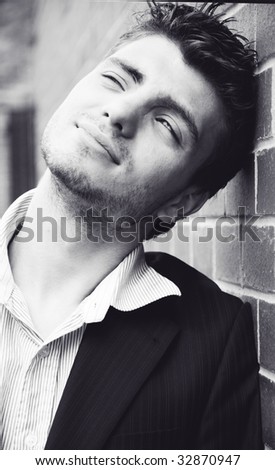Young handsome man standing near the wall smiles - black and white