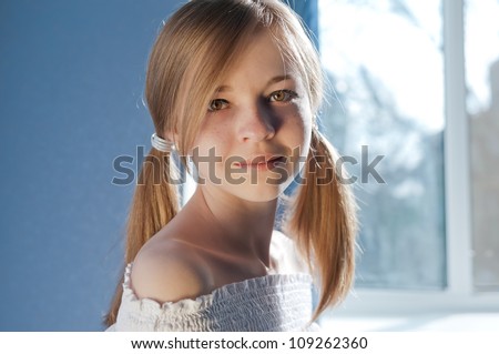 Teenage girl With Freckles and Pigtails front of window