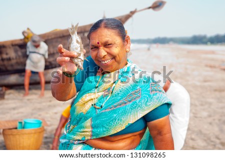 MORJIM, GOA, INDIA - MARCH 11: Indian woman show for sale fresh caught fish on a beach near fisher boat, Morjim, March 11, 2013 in Goa India. This activity will provide a income stream for people.