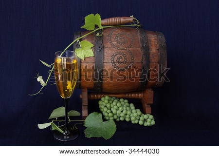 Small barrel of wine with grapes and a glass of wine.
