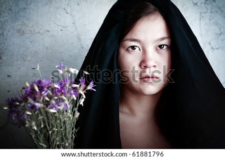 Sad girl with flowers in mourning