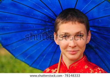 Young woman wearing chinese qipao dress holding blue parasol