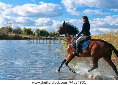 Pretty girl riding horse in shallow river water