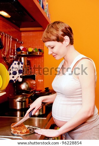 Pregnant woman with cake in kitchen