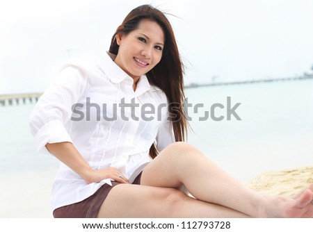 beautiful woman sitting on the beach in smiling expression