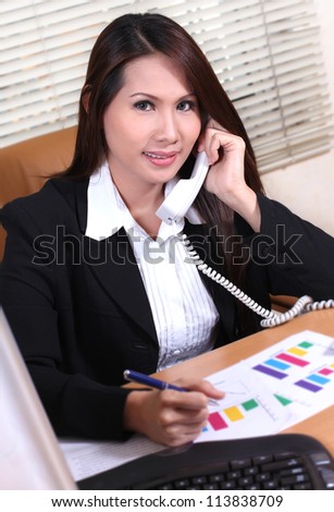 pretty business woman sitting at her desk talking on the telephone