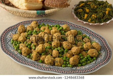 Dish with Moroccan style minced chicken balls and green peas, spinach salad and bread
