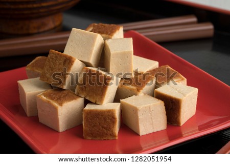 Cubes of smoked tofu on a red dish close up