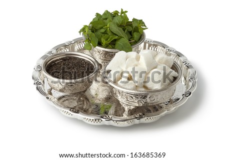 Moroccan tea set with sugar,mint and tea in traditional bowls on white background