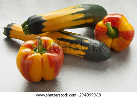 Fresh raw striped yellow and red peppers and green yellow striped zucchini