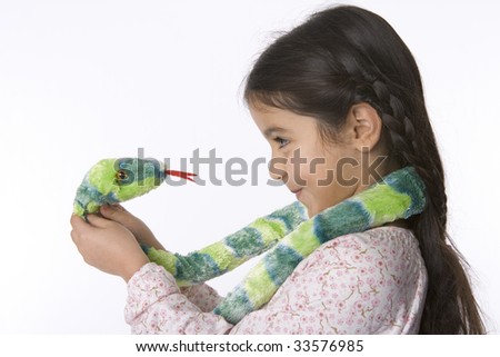Little girl is looking into the eyes of a toy snake