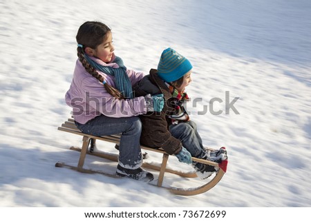 Two children on a sled having fun in the snow