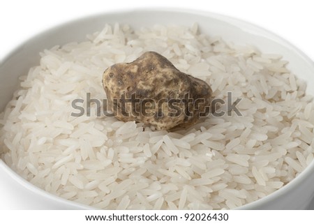 Cup of raw rice with fresh white truffle on white background
