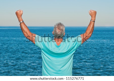 Happy and successful man cheering outdoors with a power sign with his arms