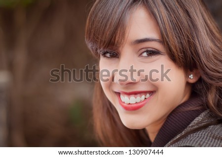 Young woman with a big smile looking at the camera on a brown coffee background