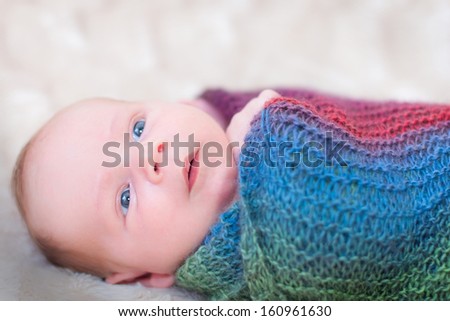Newborn baby awake and relaxed wrapped in a colourful blanket