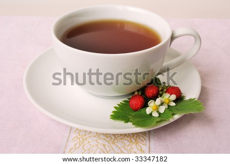 A cup of strawberry tea with blossoms and berries