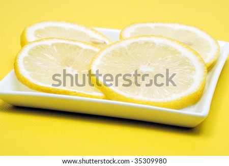 Sliced lemon on white square plate on yellow