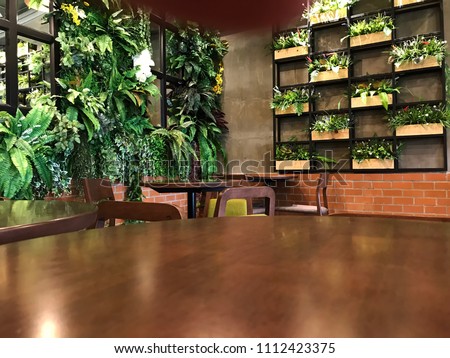 Empty wood table with artificial plant decoration on the wall of ecology design interior. Fake tree from plastic plants ornament design on the wall of green office.
