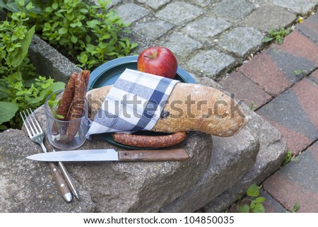 outdoor dining :    picnic food or lunch break food with fresh olive-baguette,  apple and sausages.