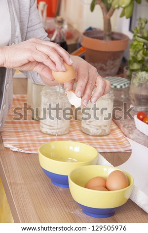 senior woman baking homemade chocolate cake, preparing the eggs. baking chocolate/stracciatella cake in a glass jar.