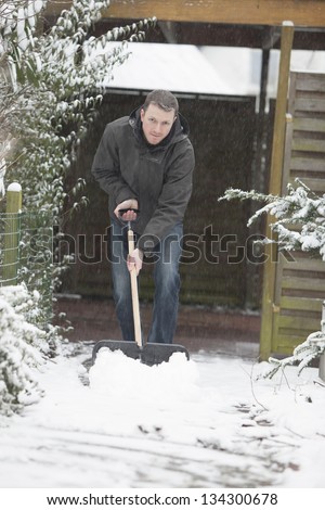 man at work. groundskeeper (caretaker service) removing snow with a shovel.
