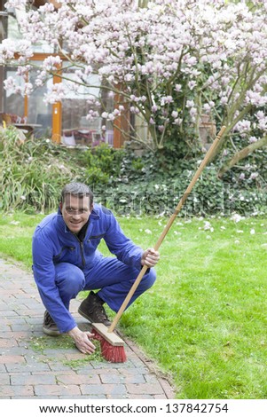 man at work.   groundskeeper  cleaning a garden path after cutting the lawn.