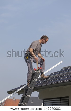 worker preparing the roof to install alternative energy photovoltaic solar panels.