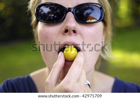 Woman bites in a fresh yellow plum