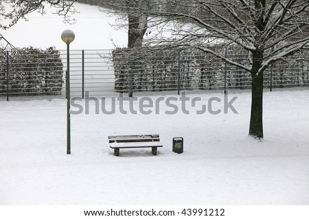 urban scene:   snow covered bench at the park