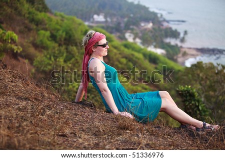woman relaxing and watching the sunset in Goa,India. location: Anjuna Beach