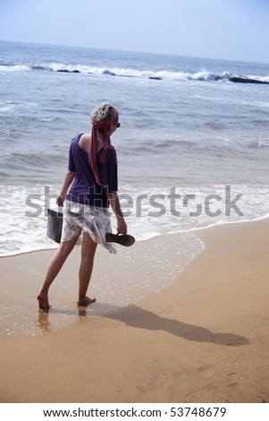 young woman walking along the beach Location: Anjuna beach, Goa, India