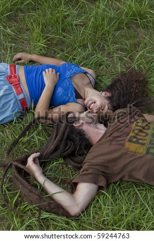 young couple in love resting face to face  on green grass.