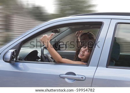 happy young couple in car. girl with thumb up.