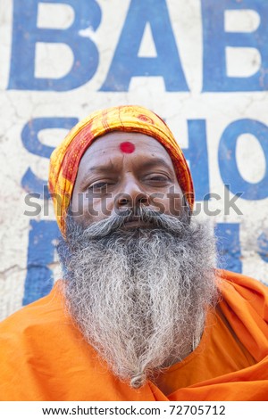 VARANASI, INDIA- MAR 01: Indian sadhu at the gate in Varanasi MAR 01, 2010 in Varanasi, India. Sadhus are ascetic, practitioner of yoga and/or wandering monks.