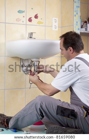 studio-shot of a plumber repairing the drain of a sink and changing a clogged pipe.