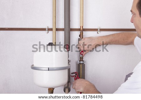 studio-shot of a heating engineer repairing and maintaining the heating system of a single-family house.