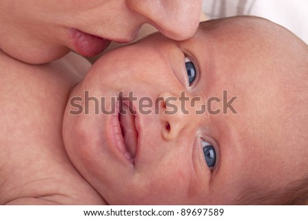 studio-shot of a mother kissing her newborn daughter to calm her down.