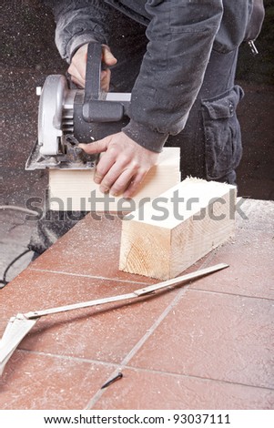studio-shot of a carpenter cutting wood with electric saw,  for furniture.
