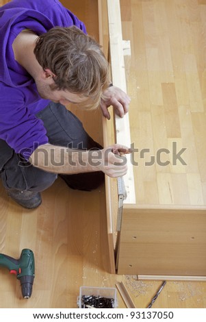 studio-shot of a carpenter using a wooden folding rule to check measurements. carpenter is building a bed.