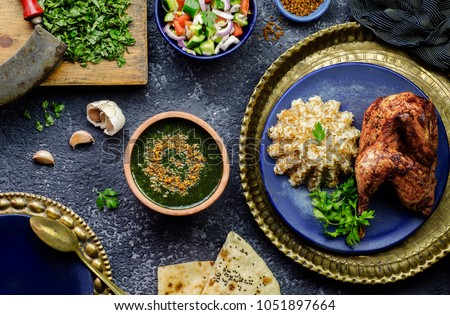 Arabic cuisine; Egyptian dish Molokhya or Molokhia placed with rice,chicken,pita bread,oriental green salad,crispy fried garlic and fresh ingredients on rustic background.