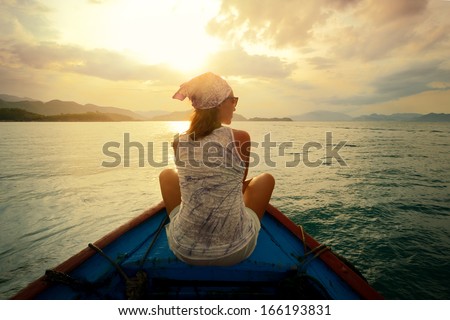 Woman traveling by boat at sunset among the islands.